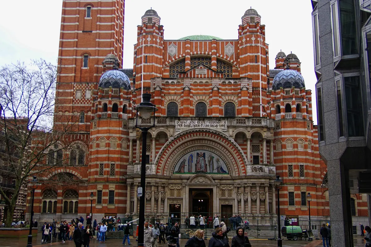 The west front of Westminster Cathedral from Victoria Street, red brick banded with stone, with domed turrets and the campanile.