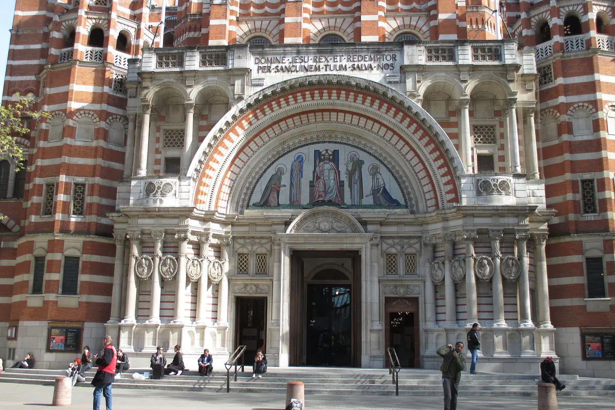 The arched central portal of the cathedral in bands of red brick and white stone, with a mosaic above the doors.